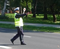 Zdjęcie przedstawia policjanta ruchu drogowego z tarczą do zatrzymywania pojazdów.