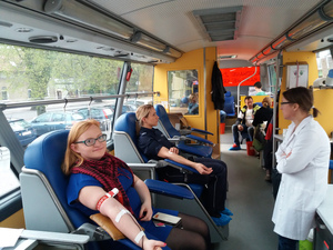 Zdjęcie wnętrza krwiobusa. Policjantka oddaje krew.