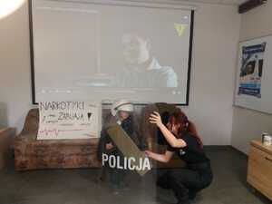 Zdjęcie przestawia uczennicę klasy policyjnej i dziecko odwiedzające stoisko policyjne.