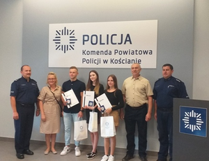 Na zdjęciu widoczny I Zastępca Komendanta Powiatowego Policji w Kościanie, Naczelnik Wydziału Prewencji KPP w Kościanie wraz z nastolatkami i ich rodzicami.