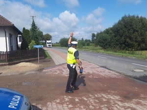 Zdjęcie przestawia policjanta zatrzymującego pojazd do kontroli drogowej.