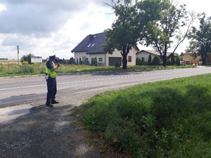 Zdjęcie przestawia policjanta dokonującego pomiar prędkości