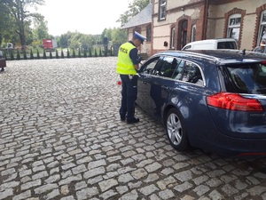 Zdjęcie przestawia funkcjonariusza przeprowadzającego kontrolę drogową.