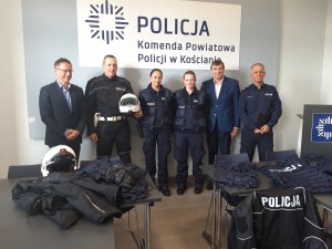 Na zdjęciu widać Komendanta Powiatowego Policji w Kościanie, Burmistrza Miasta Kościana, policjanta ruchu drogowego w stroju motocyklowym oraz dwie policjantki prewencji w kamizelkach taktycznych.