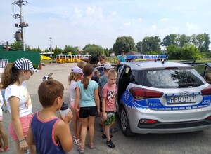 Na zdjęciu widoczne są dzieci oglądające policyjny radiowóz.