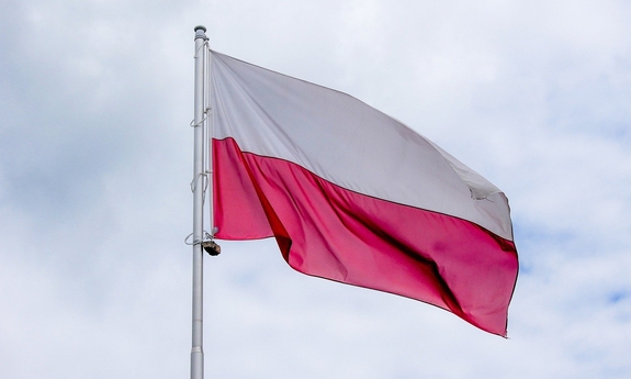 Zdjęcie przedstawia flagę Polski powiewającą na wietrze.
