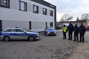 Zdjęcie przedstawia radiowóz oznakowany oraz stojących w pobliżu funkcjonariuszy.