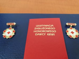 Na zdjęciu widoczna jest legitymacja Zasłużonego Honorowego Dawcy Krwi oraz dwa medale.