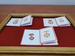Na zdjęciu widać trzy otwarte legitymacji Zasłużonego Honorowego Dawcy Krwi wraz z odznakami.