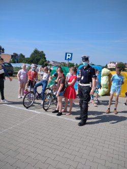 Zdjęcie przedstawia policjanta ruchu drogowego stojącego wśród grupy dzieci.