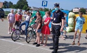 Na zdjęciu widać policjanta ruchu drogowego stojącego wśród dzieci.