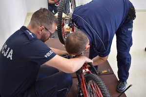 Na zdjęciu widać dwóch umundurowanych policjantów znakujących rower.