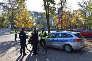 umundurowana policjantka prowadzi rozmowę z rowerzystką, obok przy radiowozie stoi dwóch policjantów